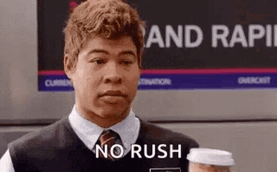 A Man In A Vest And Tie Is Holding A Cup Of Coffee And Saying `` No Rush '' . GIF