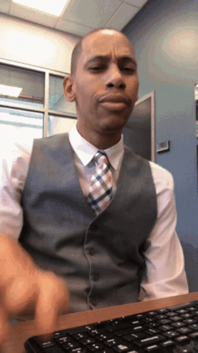 A Man In A Vest And Tie Sits At A Desk With A Keyboard GIF