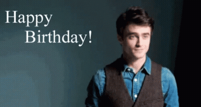 A Man In A Vest Is Standing In Front Of A Sign That Says Happy Birthday ! GIF