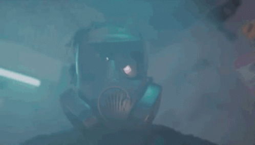A Man In A Vest Is Standing In Front Of A Wall Of Guns . GIF