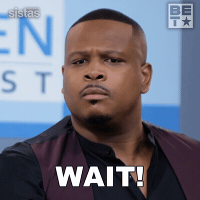 A Man In A Vest Says Wait In Front Of A Sign That Says Sistas GIF