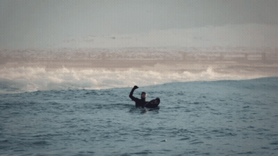 a man in a wetsuit is floating in the ocean with his hand up