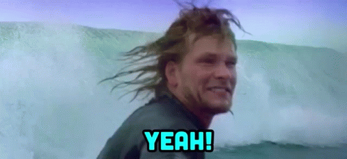 A Man In A Wetsuit Is Riding A Wave In The Ocean . GIF