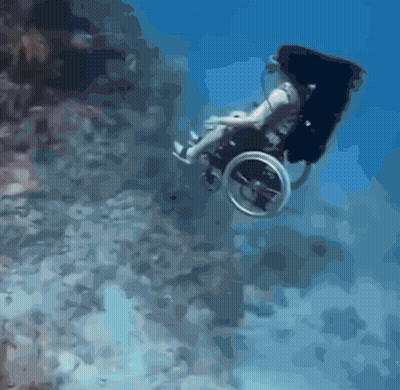 A Man In A Wheelchair Is Swimming Underwater GIF