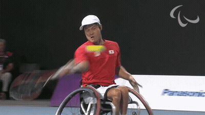 A Man In A Wheelchair Swings A Tennis Racket At A Tennis Ball GIF
