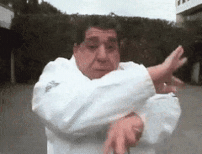 A Man In A White Adidas Jacket Is Doing A Karate Move GIF