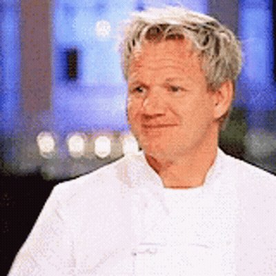 A Man In A White Chef 'S Coat Is Smiling And Looking Away From The Camera . GIF