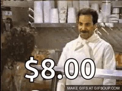 A Man In A White Chef 'S Coat Is Standing In A Kitchen With A Sign That Says $ 8.00 On It . GIF