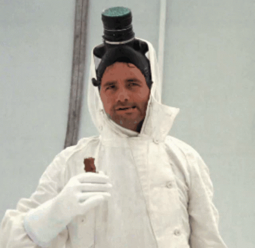 A Man In A White Coat Has A Bottle On His Head And Is Holding A Piece Of Chocolate GIF