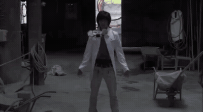 A Man In A White Coat Is Standing In A Dark Room With His Arms Outstretched And A Red Light Coming Out Of His Chest GIF