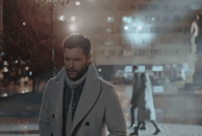 A Man In A White Coat Is Walking Down The Street GIF