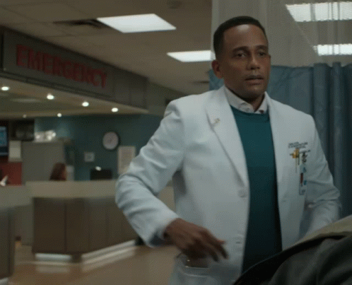 A Man In A White Coat Stands In Front Of An Emergency Room GIF