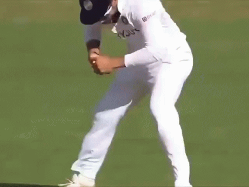 A Man In A White Cricket Uniform Is Standing On A Field And Screaming . GIF