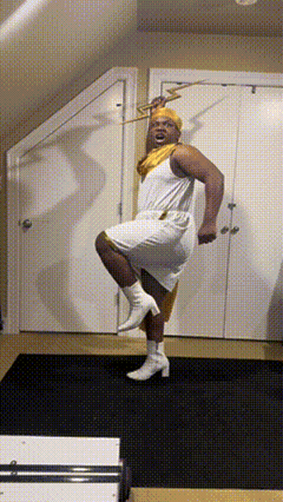 A Man In A White Dress Holds A Trumpet In His Hand GIF