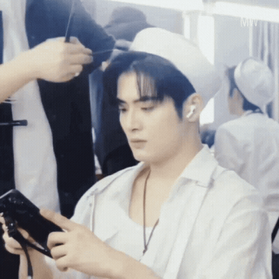 A Man In A White Hat Is Holding A Cell Phone GIF