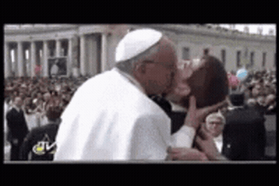 A Man In A White Hat Is Kissing Another Man In Front Of A Crowd Of People . GIF