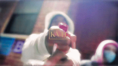 A Man In A White Hoodie Is Holding A Candy Cane In Front Of A Kn Entertainment Logo GIF