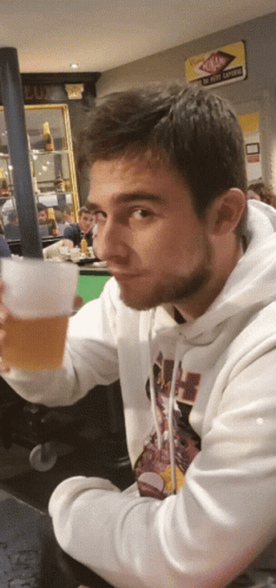 A Man In A White Hoodie Is Holding A Glass GIF