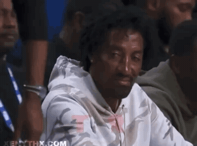 A Man In A White Hoodie Is Sitting In A Crowd And Making A Funny Face . GIF