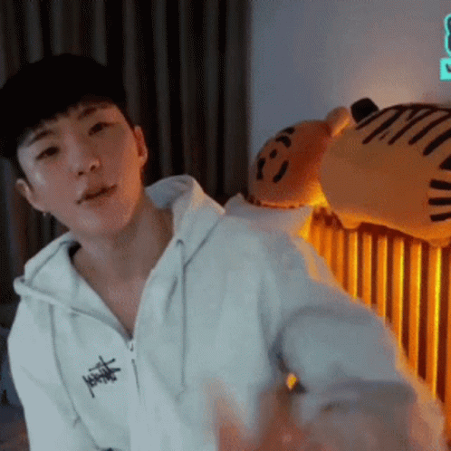 A Man In A White Hoodie Is Standing In Front Of A Stuffed Animal . GIF