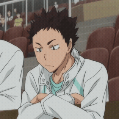A Man In A White Jacket And A Blue Shirt Is Sitting In A Stadium GIF