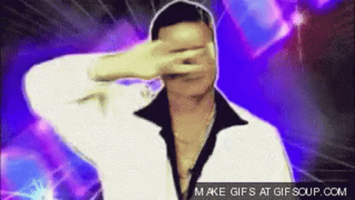 A Man In A White Jacket Is Covering His Face With His Hand . GIF