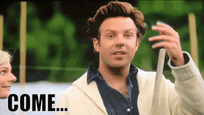 A Man In A White Jacket Is Holding A Baseball Bat And The Word Come Is On The Screen Behind Him GIF