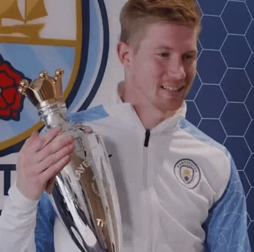 A Man In A White Jacket Is Holding A Trophy In His Hands . GIF