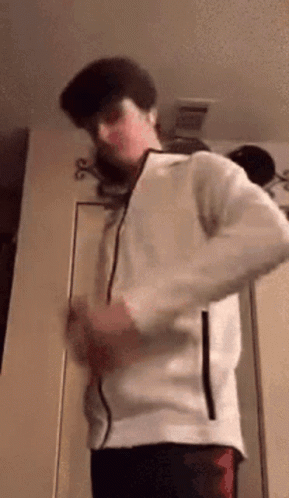 A Man In A White Jacket Is Standing In A Room . GIF