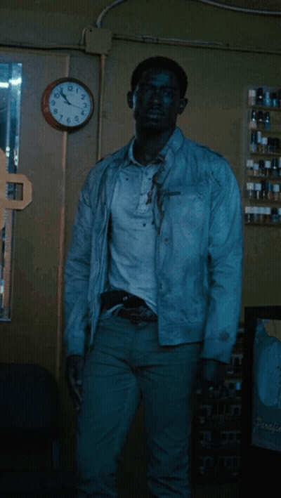 A Man In A White Jacket Is Standing In Front Of A Clock That Shows The Time As 11:55 GIF