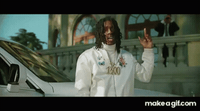 A Man In A White Jacket Is Standing In Front Of A White Car And Making A Peace Sign . GIF