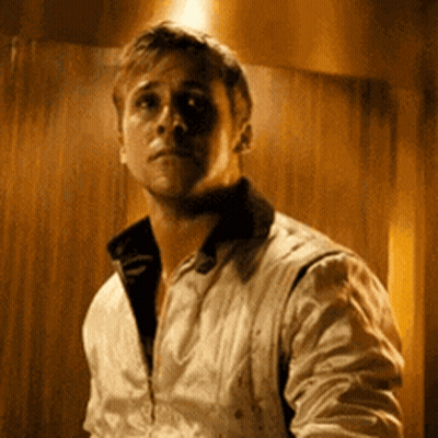 A Man In A White Jacket Is Standing In Front Of A Wooden Wall In A Dark Room . GIF