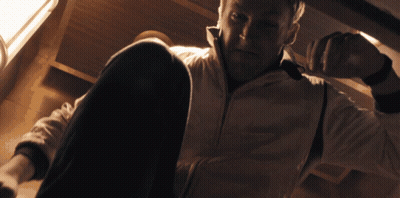 A Man In A White Jacket Sits On The Floor Looking Down GIF