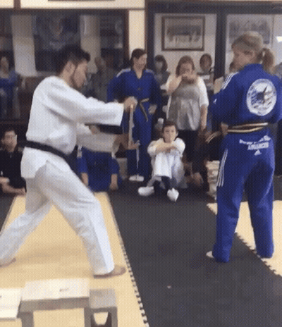 A Man In A White Karate Uniform Is Fighting Another Man In A Blue Karate Uniform . GIF