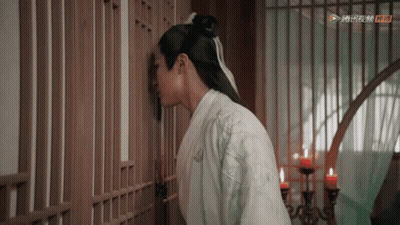 A Man In A White Kimono Is Leaning Against A Wooden Fence . GIF