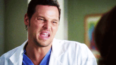 A Man In A White Lab Coat And Blue Scrubs Is Making A Funny Face . GIF