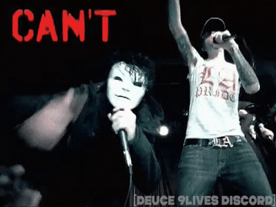 A Man In A White Mask Is Singing Into A Microphone While Another Man Stands Behind Him . GIF