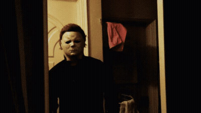 A Man In A White Mask Is Standing In A Doorway Holding A Knife GIF
