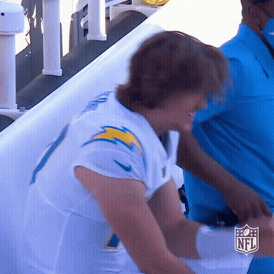 A Man In A White Nfl Jersey Stands In Front Of A White Wall GIF