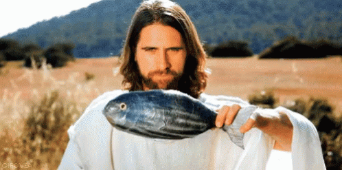 A Man In A White Robe Is Holding A Large Fish In His Hand GIF