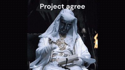 A Man In A White Robe Is Sitting In A Chair Reading A Book And Waving GIF