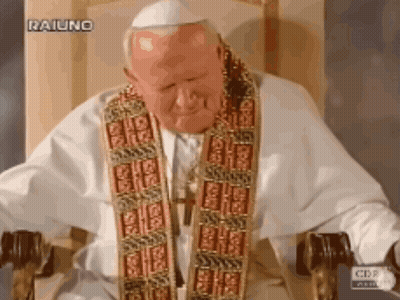 A Man In A White Robe Is Sitting In A Chair With A Cbs Logo Behind Him GIF