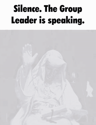 A Man In A White Robe Is Sitting In Front Of A Microphone With The Words " Silence The Group Leader Is Speaking " Above  GIF