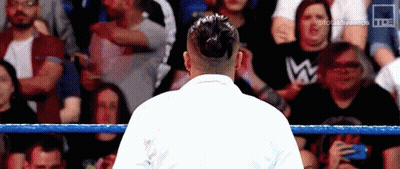 A Man In A White Robe Is Standing In A Wrestling Ring . GIF