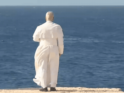 A Man In A White Robe Is Standing On A Cliff Overlooking A Body Of Water GIF