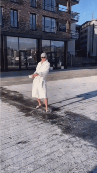 A Man In A White Robe Is Standing On A Sidewalk GIF