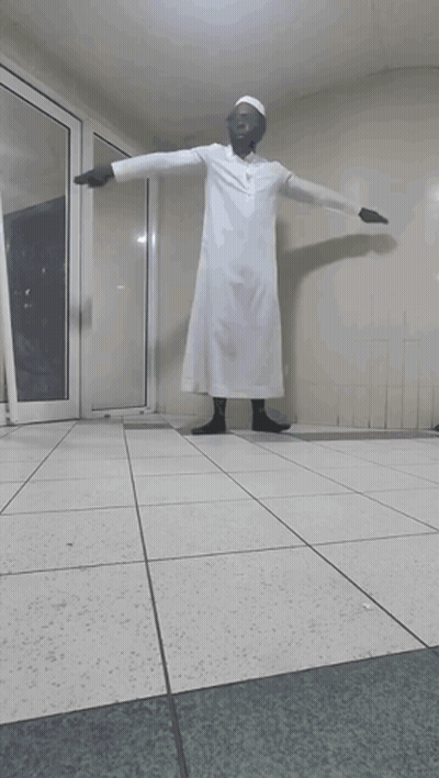 A Man In A White Robe Stands In A Hallway GIF