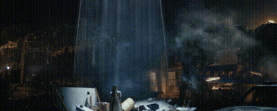 A Man In A White Robe Stands In Front Of A Burning Building GIF