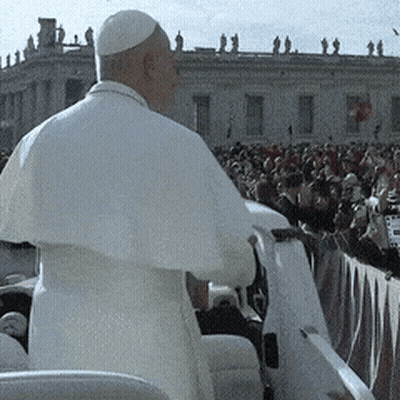A Man In A White Robe Stands In Front Of A Large Crowd GIF