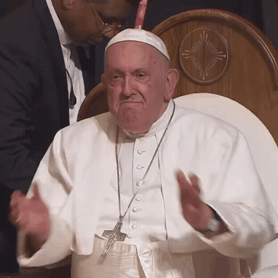 A Man In A White Robe With A Cross Necklace GIF